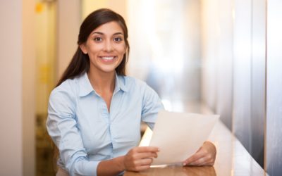 Closeup portrait of smiling at camera pretty adult Indian woman sitting at table in cafe and holding document